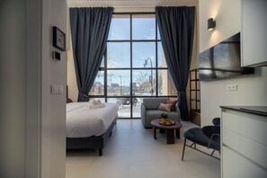 A modern hotel room with a bed, sofa, desk, and large window with curtains. - Hotel ARENA byAstiblanco (Valencia)