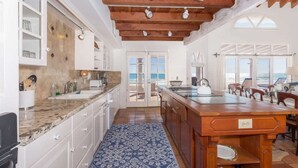 Una cocina amplia con una isla grande, armarios blancos y una alfombra azul estampada.