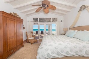 A bedroom with a large bed, a wooden wardrobe, a ceiling fan, and a view of the ocean through a glass door. - Stunning, Cozy Beachfront Home Paz de Penasco (Puerto Peñasco)