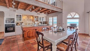 Una cocina amplia con una isla grande, armarios blancos y vistas al exterior.