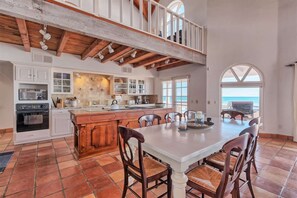 A spacious kitchen with a large island, white cabinetry, and a view to the outside. - Stunning, Cozy Beachfront Home Paz de Penasco (Puerto Peñasco)