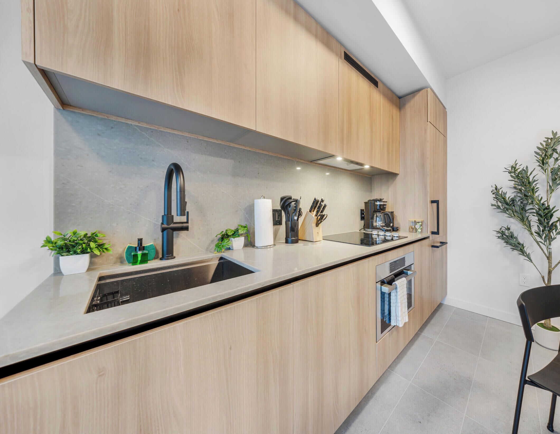 A modern kitchen with wooden cabinets, a stainless steel sink, and a built-in oven.