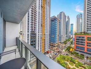 Un edificio de gran altura con varios pisos, una grúa de construcción y una vista de la calle con automóviles y vegetación.