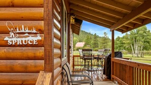 A log cabin with a wooden deck, outdoor furniture, and a sign reading 'SPRUCE'. - Lazy Trout Spruce Cabin (Greer)