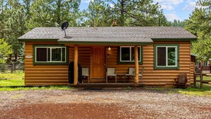 A log cabin with a porch, two windows, and a door. - Lazy Trout Aspen Cabin (Greer)