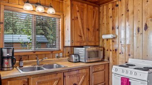 Une cuisine avec des armoires en bois, un évier, une cuisinière, un four à micro-ondes et un grille-pain.