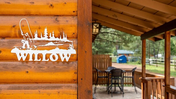Une enseigne en bois, ornée d’un logo et du mot « WILLOW », est fixée au mur d’une cabane.