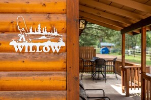 Une enseigne en bois, ornée d’un logo et du mot « WILLOW », est fixée au mur d’une cabane.