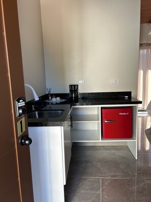 A modern kitchen with a coffee maker, a red mini-fridge, and a built-in oven. - Caroline home 1 (Quepos)