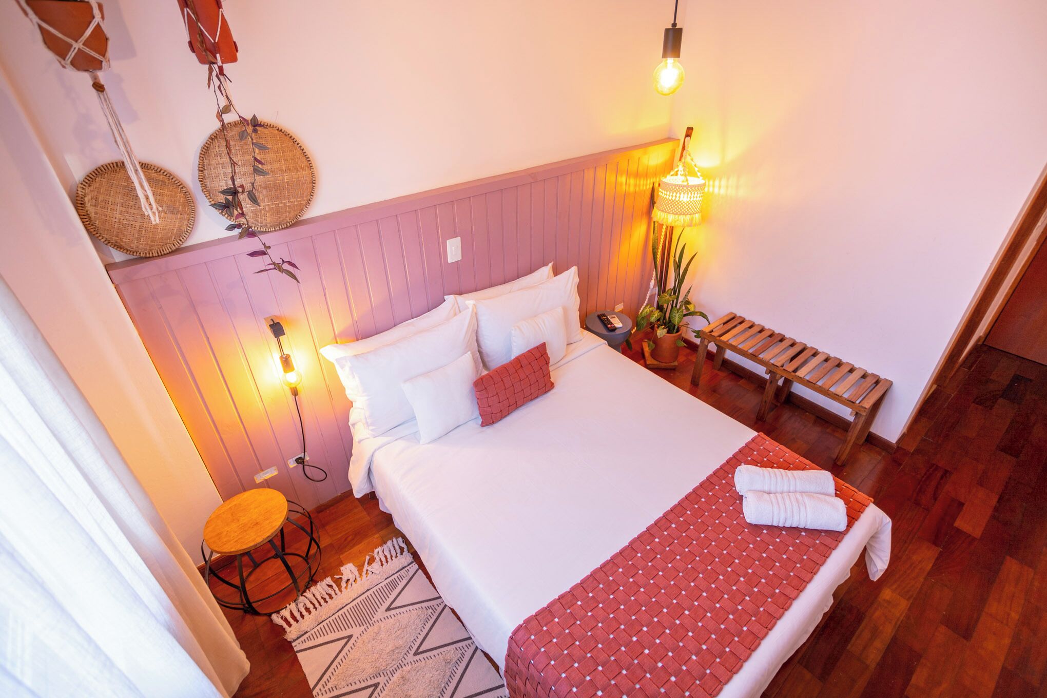Een slaapkamer met een bed, nachtkastjes, een lamp en een hangplant.
