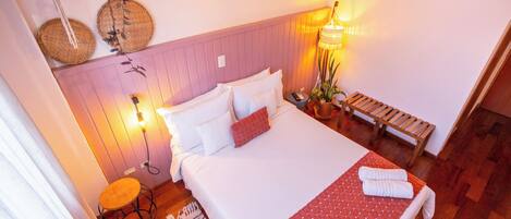 Een slaapkamer met een bed, nachtkastjes, een lamp en een hangplant.