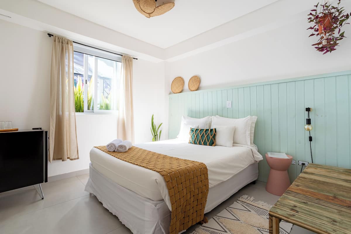A bedroom with a bed, bedside table, and a window with curtains.