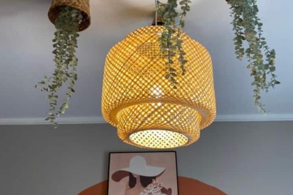 En hängande, vävd lampa med hängande gröna växter.