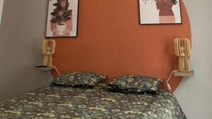 Une chambre à coucher avec un lit, un luminaire suspendu et trois tableaux encadrés accrochés au mur.