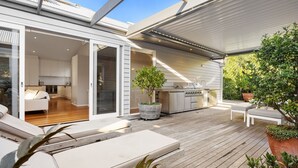 A modern house with a patio, a sliding glass door leading to a kitchen, and a barbecue area.