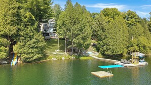 A lakeside property with a dock, a small boat, and a house surrounded by dense trees. - Luxury on Glen Lake (Eagle Lake)