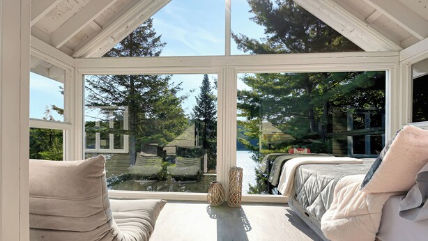 A room with a large window, a bed, and a bench. - Luxury on Glen Lake (Eagle Lake)