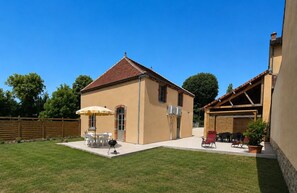 A two-story house with a covered patio, a barbecue grill, and outdoor seating. - Cozy cottage **** "Douceur et rives de Bourgogne" (Palinges)