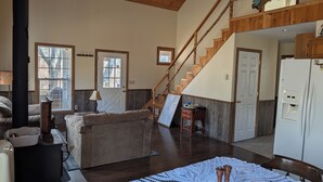 Un espacio habitable amplio con un sofá, una escalera de madera y vistas al exterior.