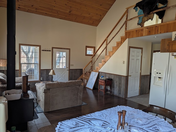 A spacious living area with a couch, a wooden staircase, and a view of the outdoors.