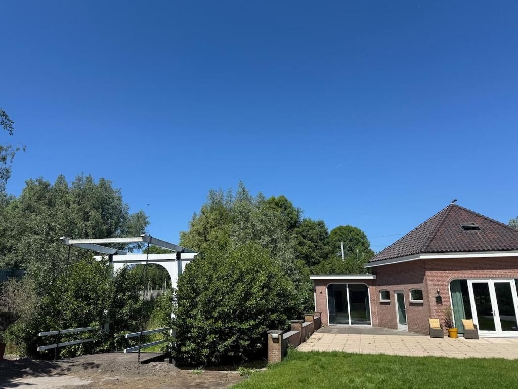 A residential property with a brick house, a covered patio, and a large tree.