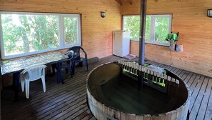 Ein Holzblockbau-Innenraum mit Whirlpool, Holzterrasse und großen Fenstern.