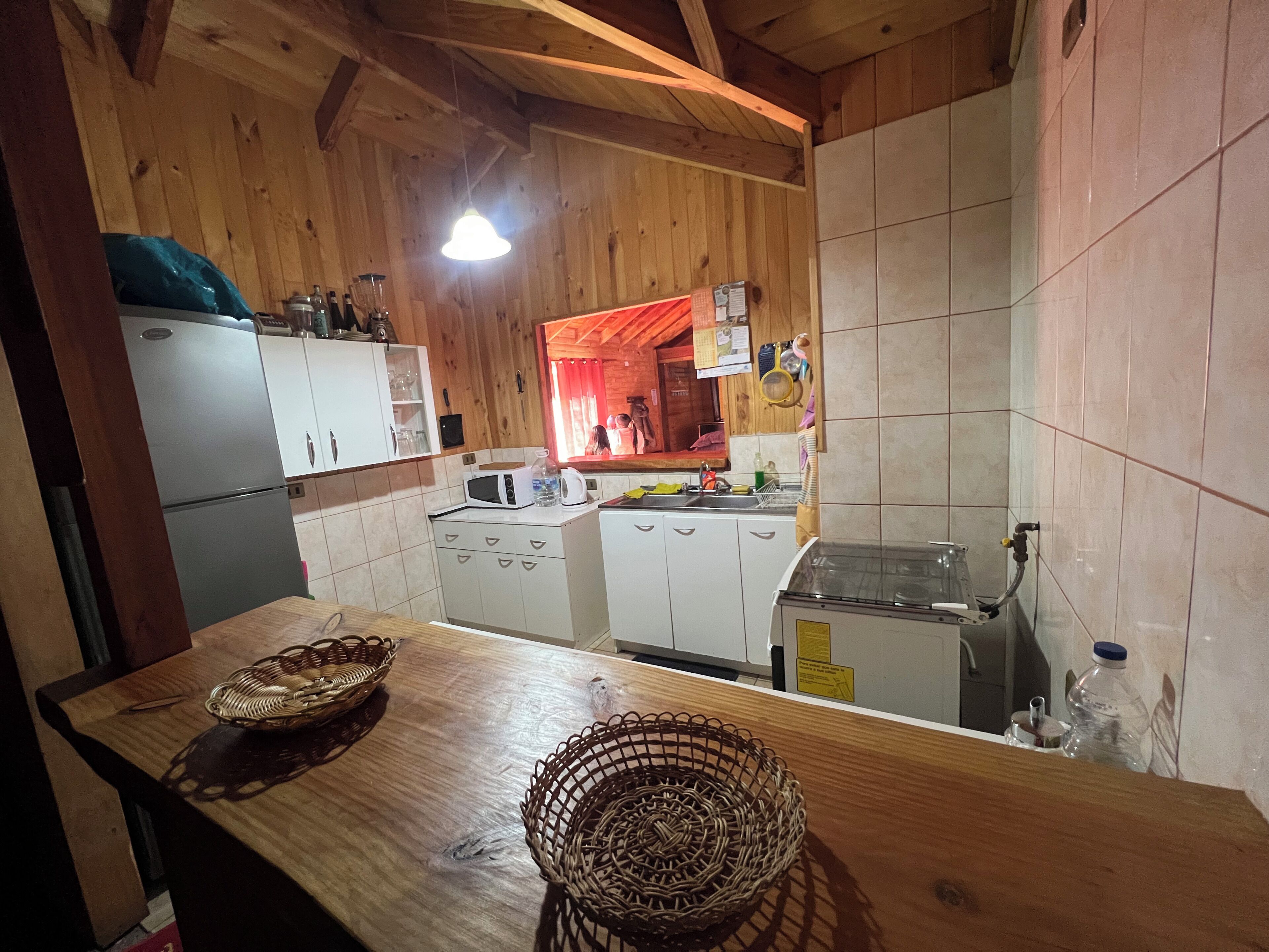 Eine Küche mit Holzschränken, einer Mikrowelle, einem Spülbecken und einem Herd.