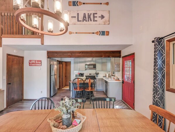 A dining area with a wooden table, chairs, a chandelier, and a sign indicating a lake view.