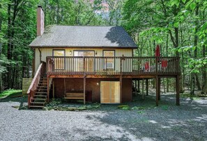 A cabin with a deck, a staircase, and a covered porch area.
