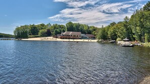 A lakeside property with a large building, a sandy beach, and dense trees. - The Salty Box Cottage in the Hideout, Lake Ariel - great location (Lake Ariel)