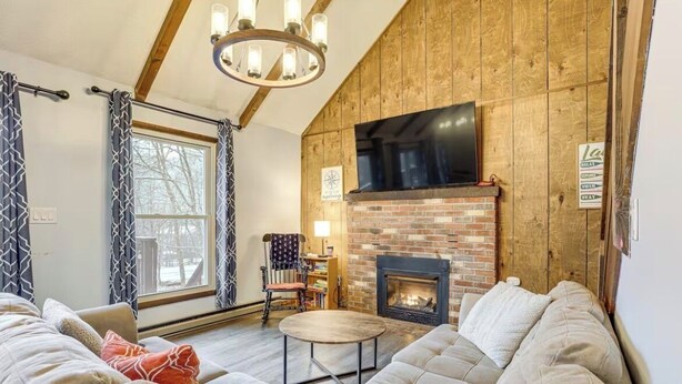 A cozy living room with a fireplace, a television mounted above it, and a large window with curtains. - The Salty Box Cottage in the Hideout, Lake Ariel - great location (Lake Ariel)