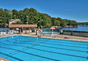 A swimming pool with lanes, a changing room, and a view of a lake.