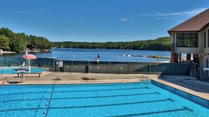 A swimming pool with clear blue water, a fenced deck area, and a view of a lake with boats. - The Salty Box Cottage in the Hideout, Lake Ariel - great location (Lake Ariel)