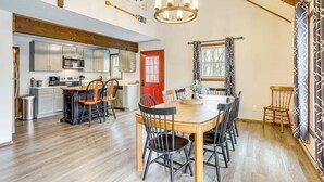 A dining area with a wooden table and chairs, a kitchen with modern appliances, and a red door. - The Salty Box Cottage in the Hideout, Lake Ariel - great location (Lake Ariel)