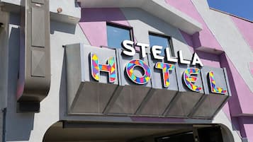 A hotel with a modern design, featuring a prominent sign that reads 'STELLA HOTEL' in bold letters.