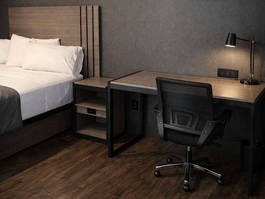 Una habitación de hotel moderna con cama, escritorio, silla y una obra de arte en la pared.