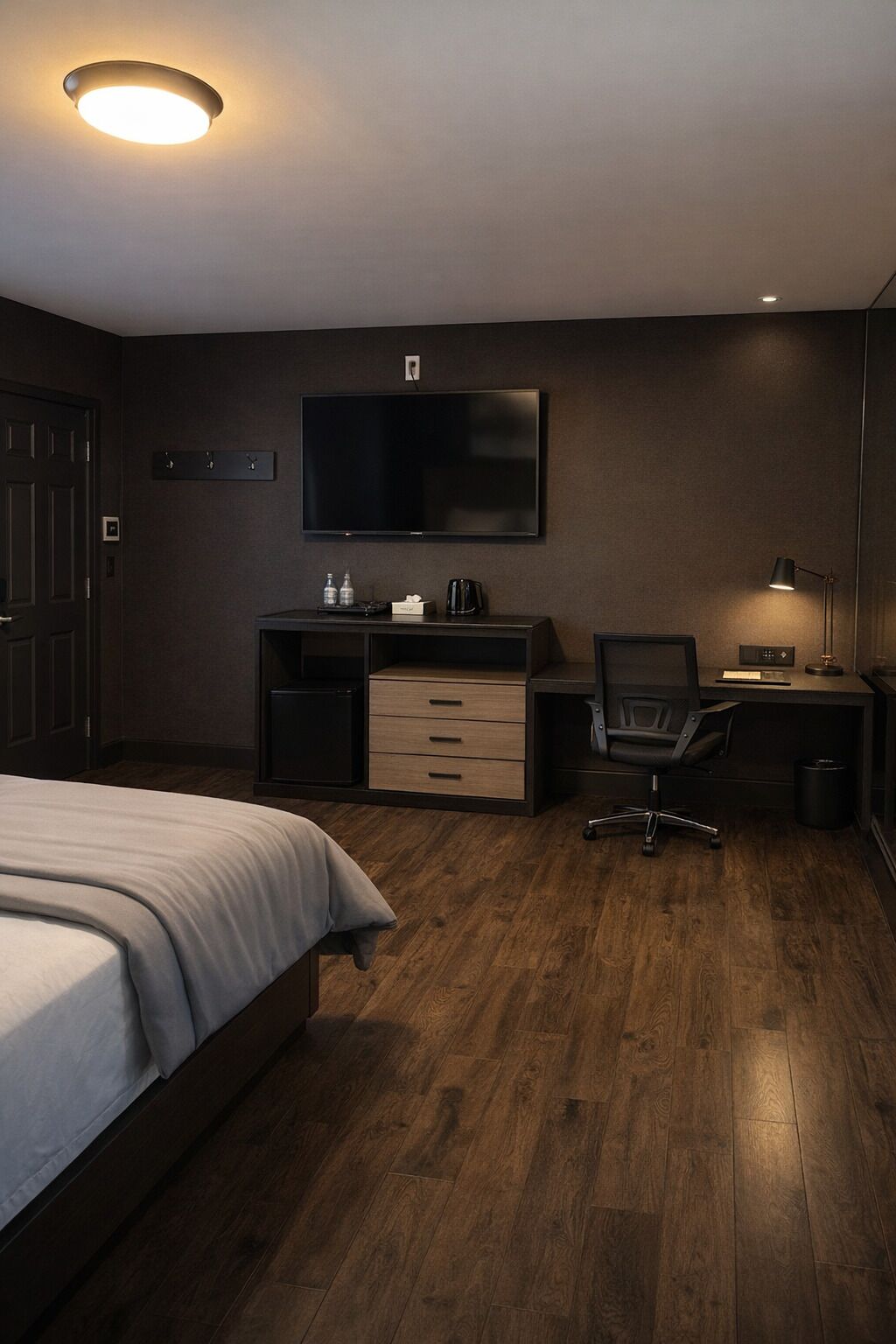 Habitación de hotel con cama, escritorio, silla, televisión de pantalla plana y lámpara de escritorio.