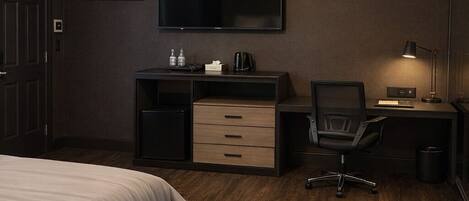 Habitación de hotel con cama, escritorio, silla, televisión de pantalla plana y lámpara de escritorio.