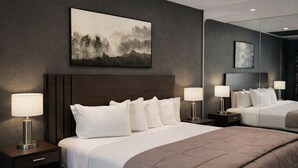 A modern hotel room with a large bed, two bedside tables with lamps, a dark wood floor, and a large painting on the wall. - Stella Hotel Bronx (Bronx)