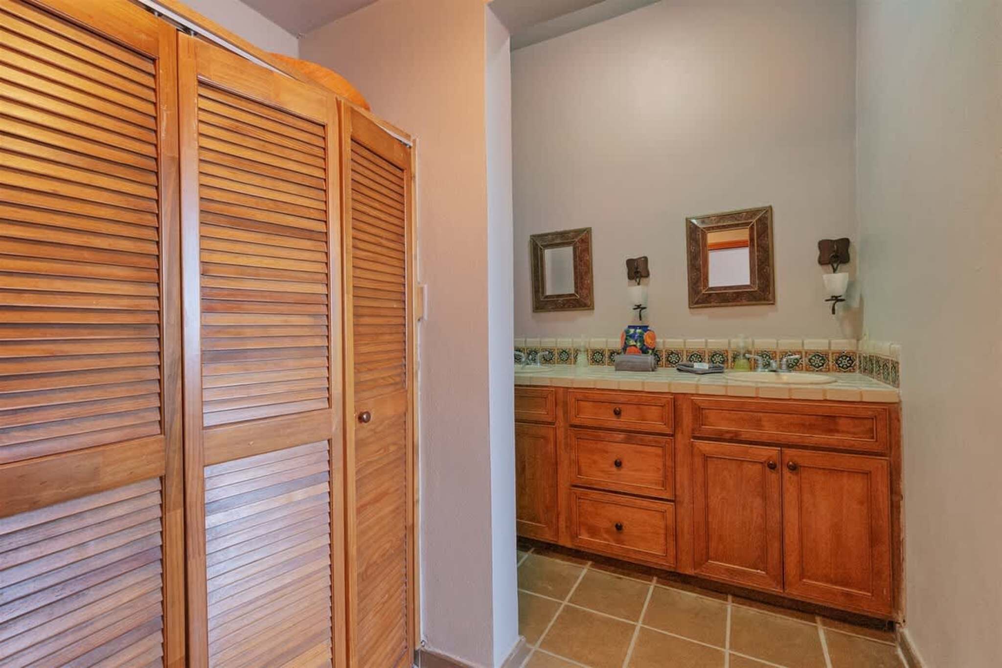 A bathroom with wooden cabinets, a tiled backsplash, and two wall-mounted mirrors.