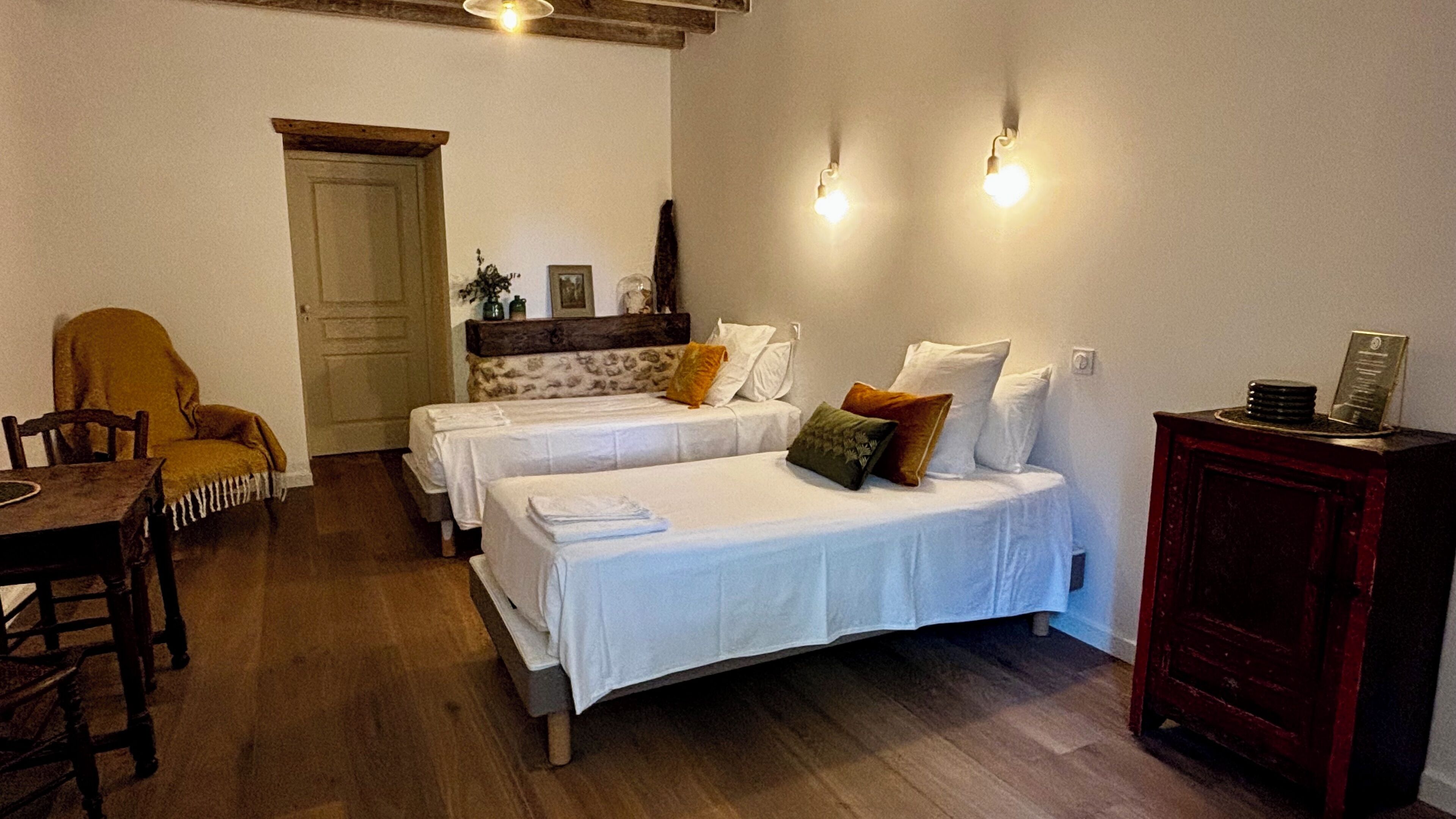 Une chambre avec deux lits, une table en bois, une chaise et un placard.