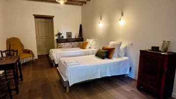 Une chambre avec deux lits, une table en bois, une chaise et un placard.
