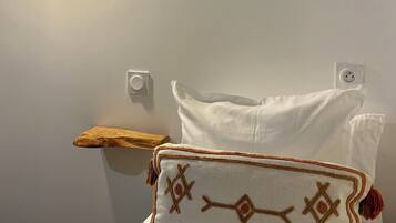Un lit avec un oreiller blanc et un coussin décoratif orné de glands.