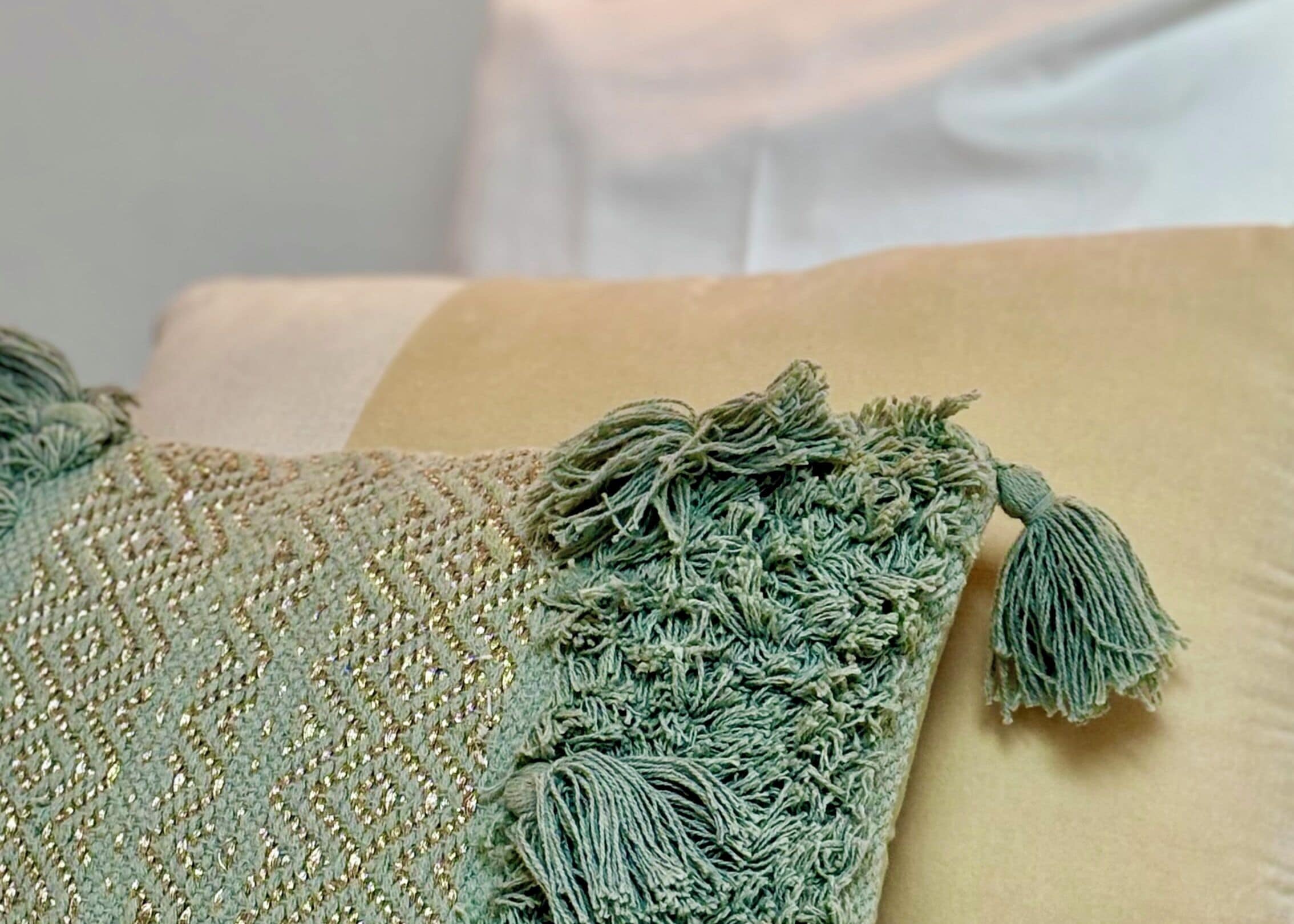 A close-up of a textured fabric with a tassel detail, likely part of a piece of furniture or decor.