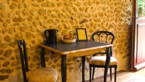 A stone wall, wooden table, two chairs, and a small table with items on it. - LE DOMAINE DU PETIT TERTRE (Sainte-Sabine-sur-Longève)