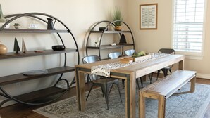 A dining area with a wooden table, benches, metal shelves, and a patterned rug. - Charming 2-Bedroom Townhome Attached Garage Near Downtown Georgetown (Georgetown)