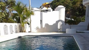 Ein klarer Pool mit weißem Zaun und Palmen im Hintergrund.