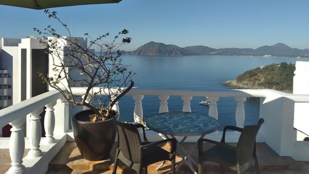 Ein Balkon mit Meerblick, einem Blumentopf und einem runden Tisch mit Stühlen.