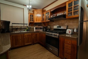 A kitchen with wooden cabinets, a stainless steel refrigerator, a microwave, an oven, and a coffee maker.