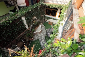 A courtyard with potted plants, a stone pathway, and a small seating area.